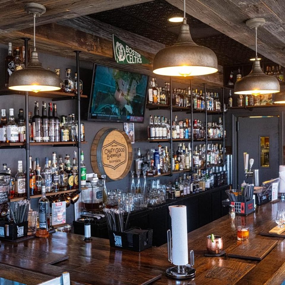 Empty Crazy Good Barbeque bar with pendant lights and shelves of spirits.